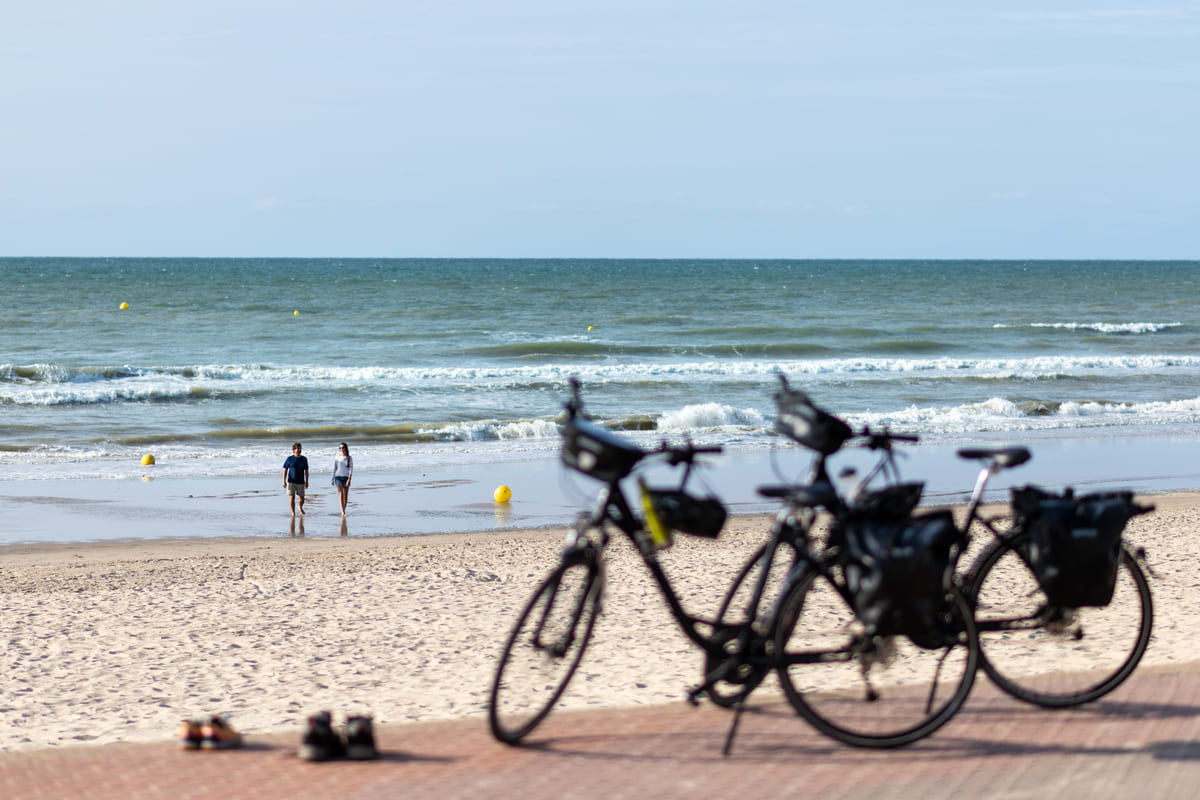 Couple de cyclistes à l'arrêt sur une plage de la Côte d'Opale