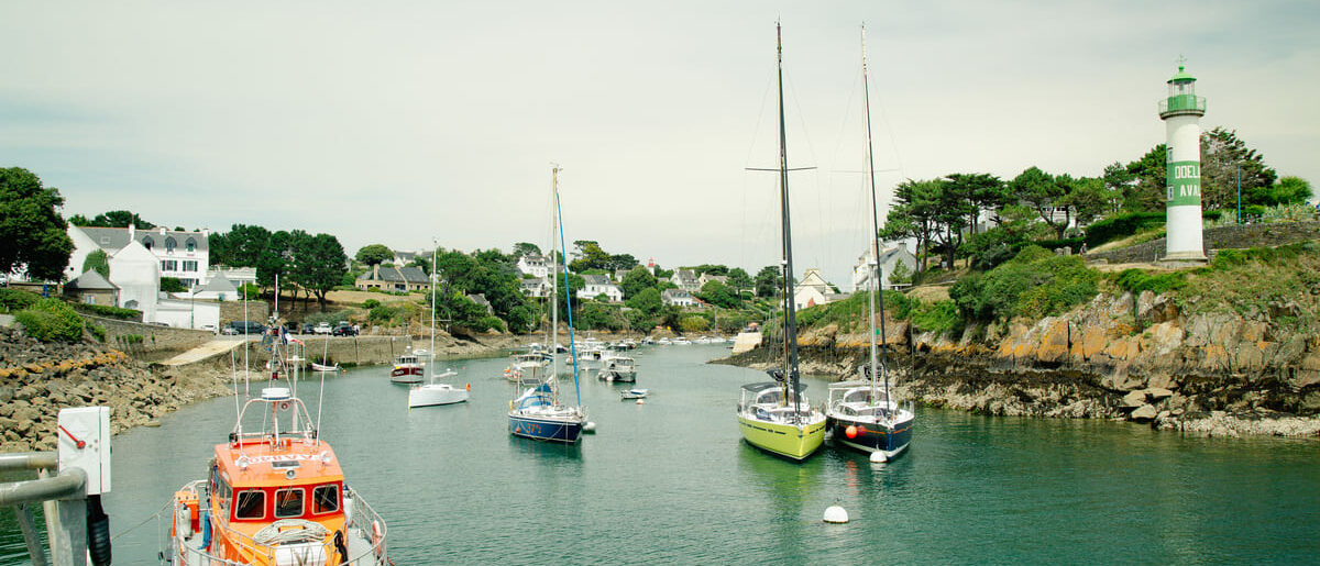 Bateaux à voile et vedettes dans le chenal du port de Doëlan entre les deux phares