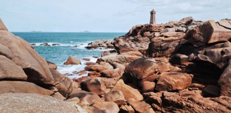 Vue sur le phare de Ploumanac’h entouré de rochers de granit rose en Bretagne