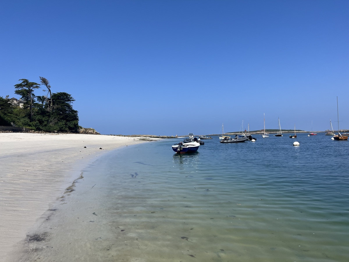 Plage de sable clair et bateaux au mouillage à Lilia.
