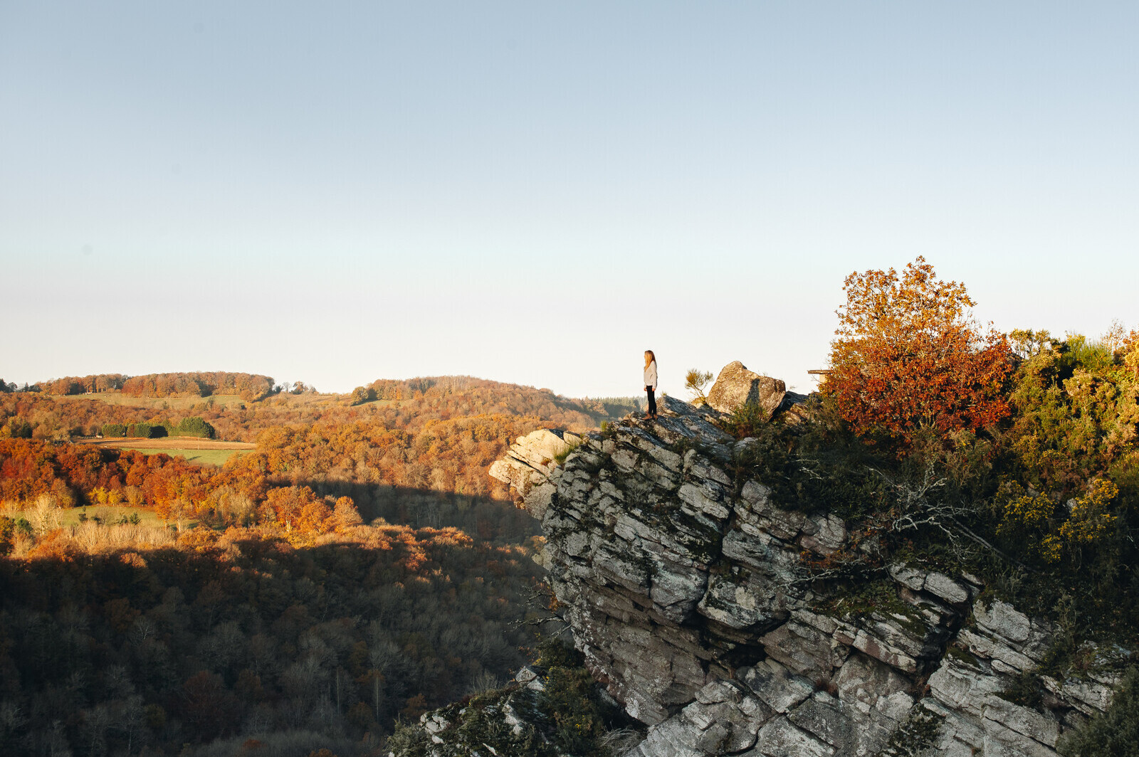 Vue sur les collines boisées de la Suisse Normande avec un promeneur en belvédère.